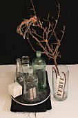 Decorative, vintage glass bottles next to bird ornament sitting on dry twig in vase
