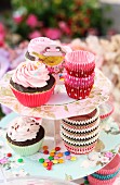Cupcakes und bunte Backförmchen aus Silikon auf floral gemusterter Etagere