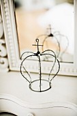 Wire crown with beaded ornaments in front of mirror on dressing table