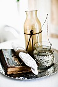 Antiquarian book and vintage-style glass containers on tray