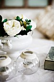 Tealight holders and white roses in china vase