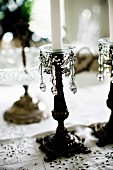 Antiker Kerzenständer mit Perlenschmuck und weisser Kerze auf Tischdecke
