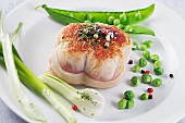 Veal fillet wrapped in bacon served with delicate spring vegetables and peppercorns