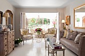 Period furniture, narrow coffee table and sofa in elegant interior with antique armchairs in front of open French windows