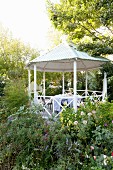 Gazebo with corrugated metal tent roof surrounded by blooming flowerbeds