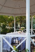 Round table with tablecloth and garden chairs in gazebo
