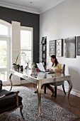 Woman sitting at postmodern, silver desk in elegant study