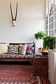 Sofa mit folkloristisch gemusterten Kissen, darüber Trophäe im Wohnzimmer mit marokkanischem Flair