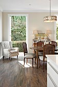 Antique, Rococo-style chairs and dining table; armchair next to open terrace door in background