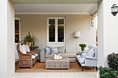 View from garden of loggia furnished with wicker armchairs and upholstered seating