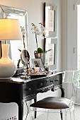 Plexiglas chair at antique, dark-wood dressing table with table lamp with pale lampshade