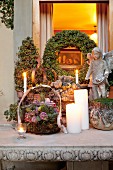 Flower arrangements in wire baskets and lit candles on festively decorated terrace table