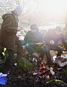 Friends eating pizza around a campfire in winter