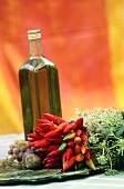 A Mediterranean arrangement of olive oil, chilli peppers, herbs and fruits