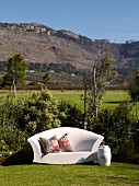 Outdoor Sofa in Weiß mit folkloristischen Kissen im Garten, im Hintergrund Berglandschaft