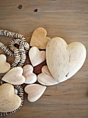 Wooden hearts of different sizes and string of beads on surface