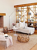 Wicker pouffe and chaise longue in front of wooden partition shelving