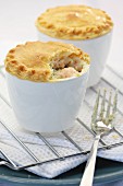Two mini salmon pies in baking dishes on a wire rack