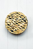 A whole blueberry pie with a lattice top in a baking tin