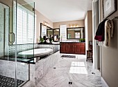 Eingebaute, ovale Badewanne hinter Glas Duschkabine in luxuriösem Bad mit Marmorboden