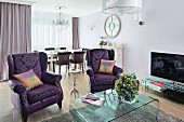 A sitting area in an elegant mix of styles with classically patterned, purple winged armchairs and a modern acyrl table