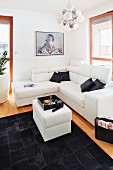 Decorative cushions on a white corner sofa in front of a patchwork leather rug in contrasting black