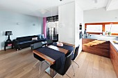 Offener Wohnraum mit weißem Raumteilerschrank zwischen Küche und Sofabereich; Esstisch mit schwarzen Stühlen