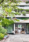 Mehrstöckiges Wohnhaus - davor Terrasse mit grossformatigen Steinfliesen, offene Terrassentür und Blick in den Wohnraum