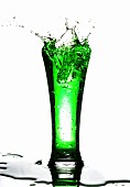 A green drink splashing out of a glass