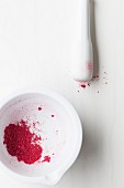 Crushed dried raspberries in a white mortar with a pestle
