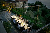 View down onto terrace of Italian farmhouse at twilight with large group of people enjoying dinner