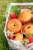 Strawberry muffins in a wire basket in a meadow