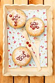 Mini cakes with redcurrants and icing sugar on a wooden tray