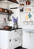 Nostalgic, vintage kitchen with wall-mounted shelf, cooker and copper pots and pans