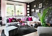Comfortable corner sofa, grey patterned wallpaper, hot pink scatter cushions and family photos on wall