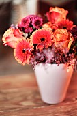 Herbstlicher Blumenstrauß in weisser Vase auf Holztisch