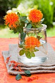 Three safflowers in a glass of water as a centrepiece on a garden table