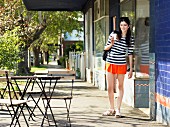 Junge Frau mit Kaffeebecher zum Mitnehmen im Straßencafe