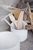 Wooden cutlery in a porcelain cup on a rustic wooden table