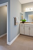 Blick in offenes Badezimmer mit blauen Wänden, Waschtisch & Badspiegel