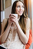 Junge Frau hält große Tasse mit Kaffee