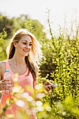 Young woman strolling amongst sunlit bushes