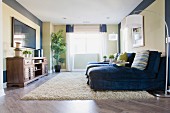 Wohnzimmer mit blauen Farbakzenten, grosszügigen Loungesesseln, Bogenlampen & Flachbildschirm über Sideboard