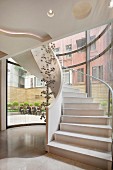 Weisser Treppenaufgang mit Wendeltreppe & Dekoobjekt aus Kugeln in Luxus-Hotel