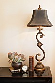 Lamp, books, clock and vase on console table against wall