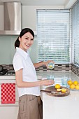 Smiling young woman cutting lemons in kitchen