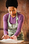 A young black woman kneading dough