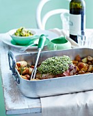 Roast lamb with a herb crust and potatoes in a roasting tin