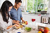 A young oriental couple making sandwiches in a kitchen