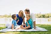 A family sitting on picnic blanket with tow little boys eating ice cream sticks at Newport Beach, California, USA
